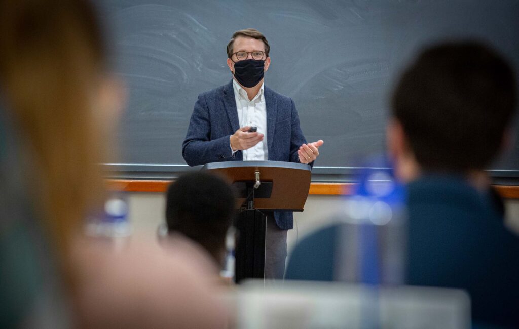 Man at front of classroom, masked